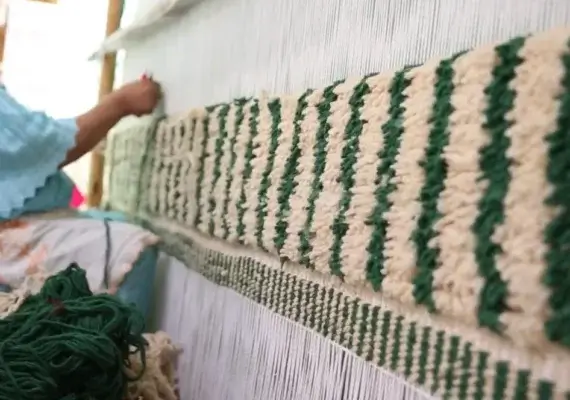 Artisane marocaine nouant un tapis berbère dans les montagnes de l'Atlas.